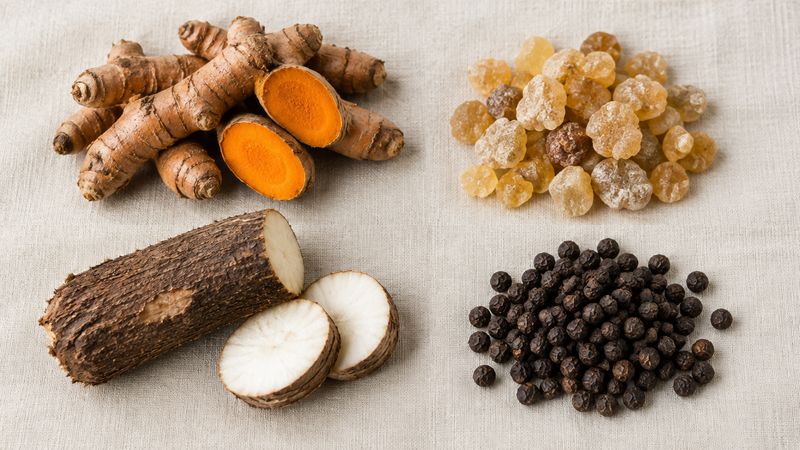 Turmeric root, boswellia resin, yucca root and black peppercorns arranged on linen